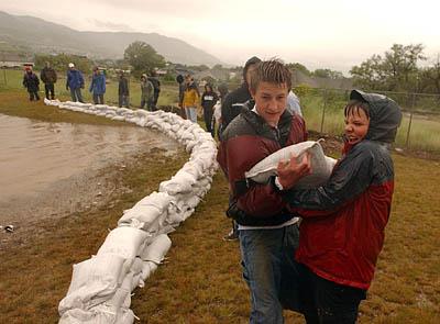 Volunteers place sand bags on the edge of a retaining pond near the Bear Hollow subdivision in Draper.