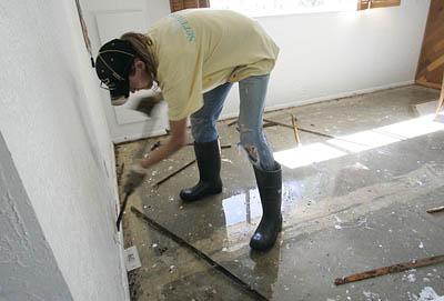 Eddie Wyman of Servicemaster removes contaminated flooring from the home of Paul Nicholson.  Despite the sand bagging efforts to keep water out, sewage and water crept up the pipes.