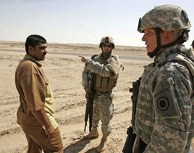 Lt. Brad Triplett, right, talks with a truck driver by using interpreter Ozro Hamblin, of Vernal, Utah, about pulling his truck out of the sand in the western Al Anbar province, which shares a border with Syria and Jordan.; 2:22 p.m. Iraq; 4:22 a.m. Utah