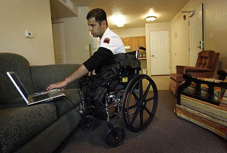 Diyar Al-Bayati, a former interpreter in Iraq who lost his legs there, works on his computer as he waits for a friend to pick him up Wednesday from his Salt Lake City apartment.