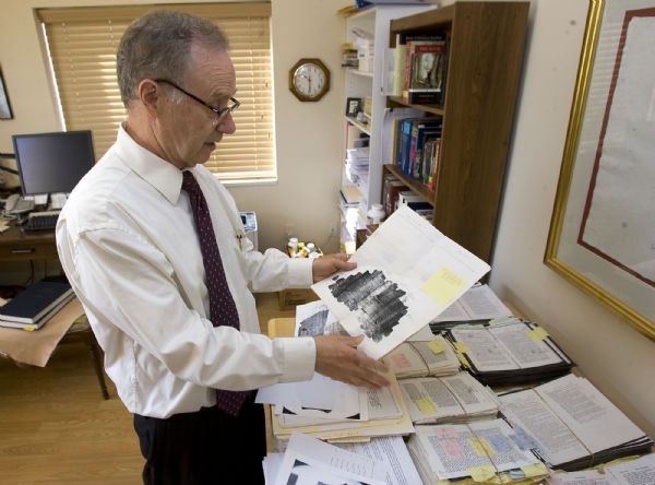 Royal Skousen has spent years researching the original manuscripts of the Book of Mormon to analyze the changes in text that have occurred along the way.   In his home office he goes through 20 editions of the Book of Mormon dating back to the early 1800's that he's used to track evolution of the text from original to the present day.   Here he looks at a photocopied fragment of the original manuscript.  He will release a book this month that brings the Book of Mormon's text as close to that original copy as possible.   Al Hartmann/The Salt Lake Tribune   9/9.2009