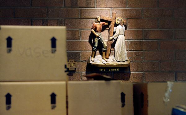 One of the Stations of the Cross from the old St. Therese of the Child Jesus Catholic Church hangs on the wall of the new building as boxes of other items from the old church wait to be unpacked Monday.The church suffered a fire two years ago and has undergone a remodeling. The  reopening is Sunday.