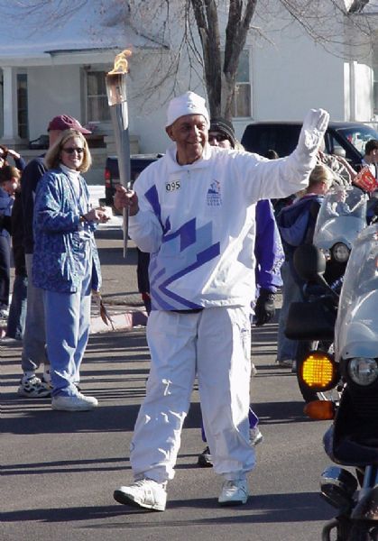 Wilbur Braithwaite, Manti, Ut., carries the Olympic Torch down Main street Tuesday, February 5, 2002. The entire community came out to cheer for the former Manti High School coach. Manny Mellor/The Salt Lake Tribune