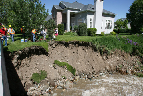 With her yard slowly slipping into Little Cottonwood Creek, Penny Sim, second from right, gets help from Sandy City crews and neighbors as she digs up plants in her yard before the city crew started securing the bank with boulders as runoff water from Little Cottonwood Creek cuts into the river banks threatening homes in the area of 8900 South 3100 East in Sandy and Salt Lake County Monday, June 7, 2010.  Steve Griffin  |  The Salt Lake Tribune