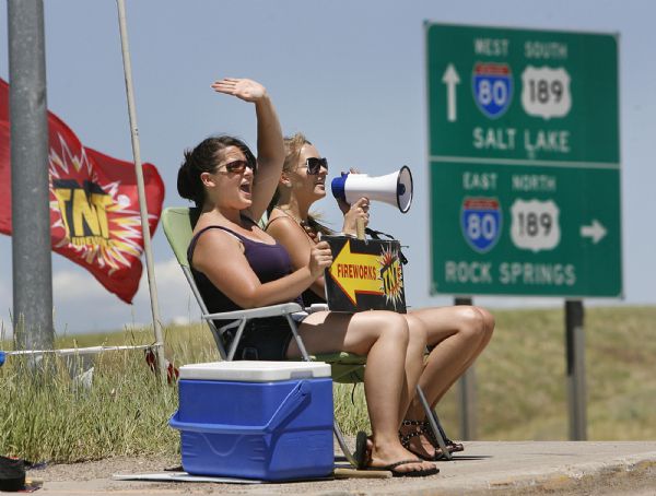 Scott Sommerdorf  l  The Salt Lake Tribune

Rebecca Norris (left) and Nichole Johnson (cq) wave and shout at potential customers from an intersection near the I-80 freeway offramp in Evanston Wyoming. They were trying to direct customers to the TNT Fireworks store further down the road, Friday, July, 2, 2010.