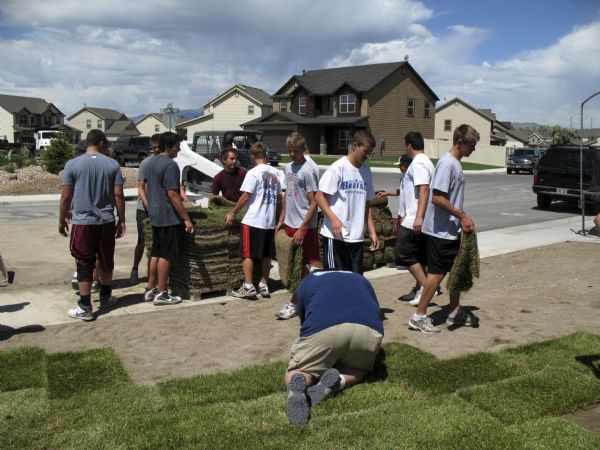 Jordan High School football players lay sod in the Lehi front yard of ...