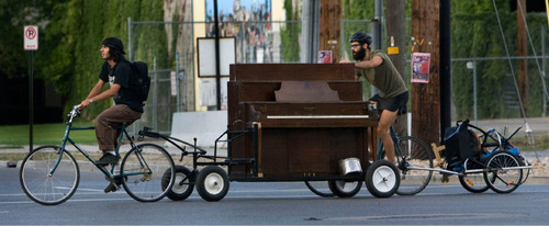 Steve Griffin  |  The Salt Lake Tribune

Corbin Baldwin, left, pulls as Eric Rich pushes their upright grand piano from their bikes on their way to perform at the Farmers Market in Salt Lake City on August 7. The piano-bike was the idea of Rich, who, with the help of his brother, made the frame for the piano and modified a bike to pull it.