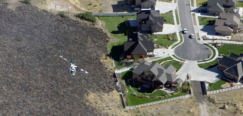 Steve Griffin  |  The Salt Lake Tribune&#xA; &#xA;A helicopter brings water in a large bucket to hotspots on the mountain south west of Herriman Monday, Sept. 20, 2010. Flames were stopped short of this subdivision.
