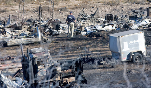 Al Hartmann  |  The Salt Lake Tribune&#xA;Police officer takes in the damage to the property of the Burns residence in Herriman on Tuesday, Sept. 21st.   It was one of the three homes burned in the Machine Gun Fire.