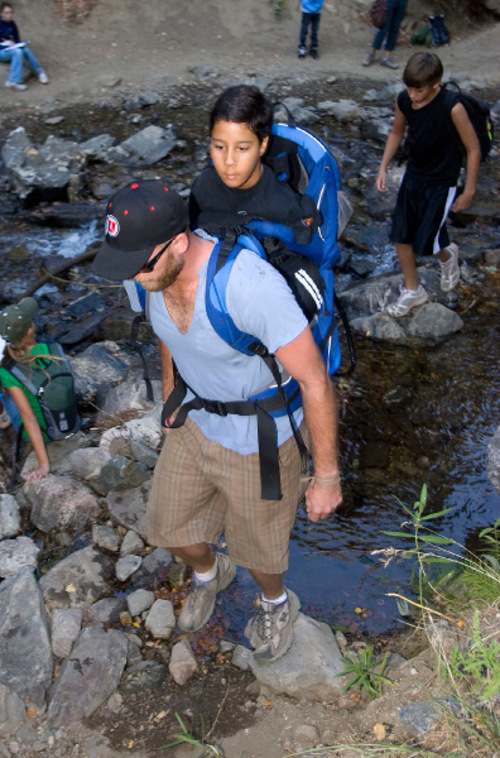 Al Hartmann  |  The Salt Lake Tribune&#xA;Gabe Adams, who does not have arms or legs, joined sixth-graders from Kaysville Elementary on Thursday to hike Adams Canyon above Layton. His older brother Brennan Adams carried Gabe in a backpack on the hike. Here, they cross a stream to get to the first study area.