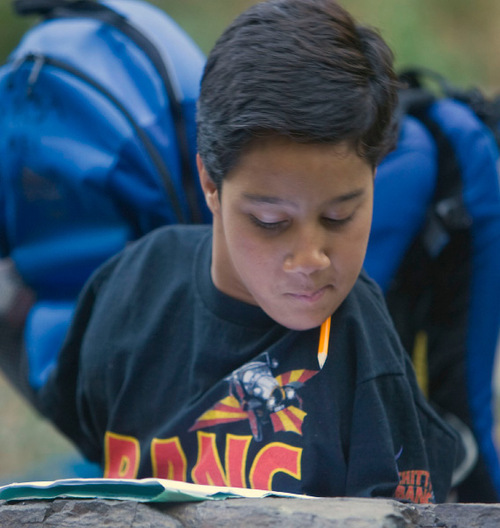 Al Hartmann  |  The Salt Lake Tribune
Gabe Adams, 11,  who does not have arms or legs, reads a work sheet Thursday during a stop on a hike in Adams Canyon with fellow sixth-graders from Kaysville Elementary. He uses a pencil tucked between his shoulder and chin to write.