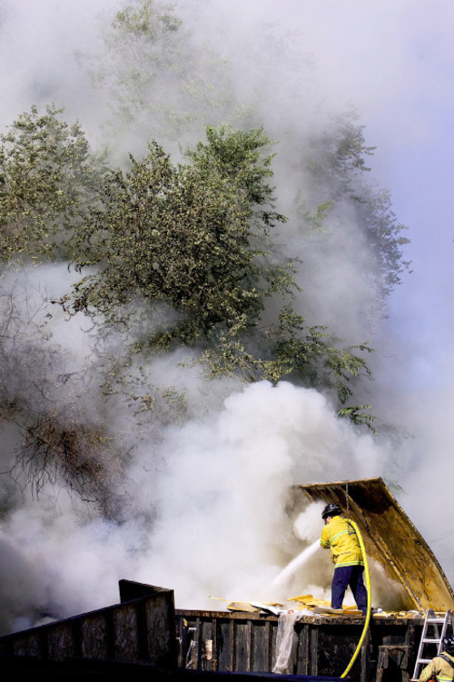 Djamila Grossman  |  The Salt Lake Tribune&#xA;&#xA;A firefighter uses a hose to spray a large burning dumpster near the intersection of 900 South and 400 West in Salt Lake City, Sunday, Oct. 3, 2010.