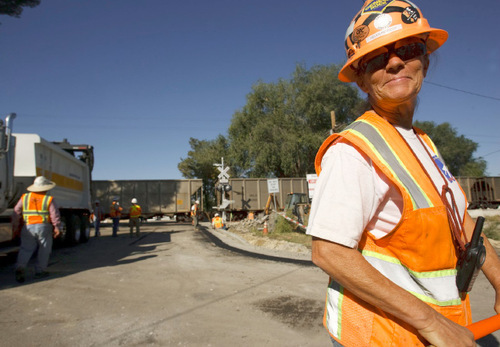 Leah Hogsten  |  The Salt Lake Tribune Helen Kennedy directs asphalt trucks at the site.  UTA contractors are laying the new FrontRunner South commuter-rail lines.