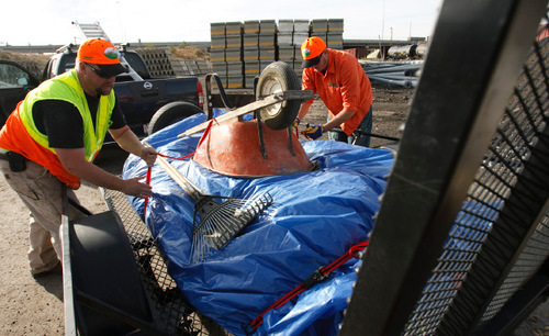 Leah Hogsten  |  The Salt Lake Tribune
  UDOT workers Jake Brown (left) and C J Connor show how to properly secure loads by wrapping items in a tarp, securing the tarp together with zip ties, covering the tarp with heavy objects and securing the items. UDOT  officials held a press conference Friday, October 29, 2010, in Salt Lake City to talk about the danger of road debris, to encourage people to secure loads properly. Utah Jazz television commentator Alema Harrington was injured Oct. 1, 2010 when a 20 pound piece of steel crashed through his windshield and broke his arm on I-15.