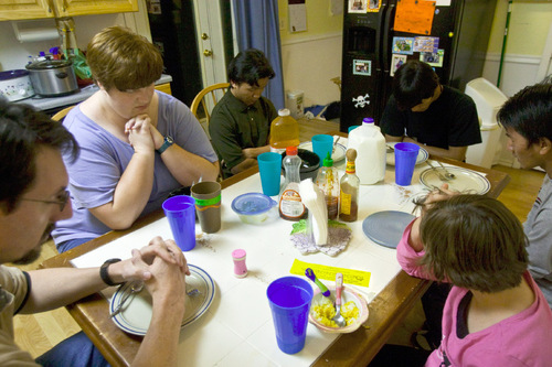 Chris Detrick  |  The Salt Lake Tribune &#xA;(Clockwise from left) Ray Osborn, Sarah Osborn,  Kap Tung, 17, Than Htay, 18, Khup, 18, and Allie, 9, pray before dinner at their home in West Valley City Thursday November 4, 2010.  Sarah and Ray Osborn are foster parents to three refugee boys from Myanmar. They also have an adopted daughter. The family is being honored by Catholic Community Services at a Nov. 10 banquet.