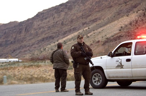 Djamila Grossman  |  The Salt Lake Tribune

Two State Park rangers stand guard with rifles at the blocked SR 279 near Moab, Saturday, Nov. 20, 2010. The road has been closed to the public while officers search for a suspect in an officer-involved shooting.