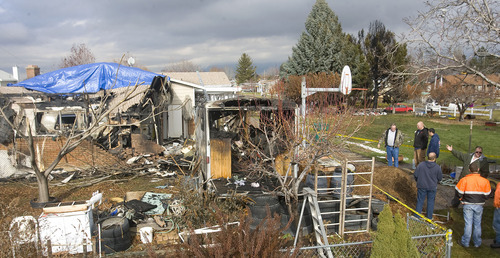 Al Hartmann  |  The Salt Lake Tribune 
Neighbors check out the damage to the trailer, garage and back bedroom  of Ned and Pat Newman's home at 2079 W. 4300 South in Roy.  The crashed plane landed in the pine trees at top, right.