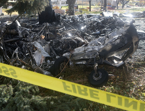 Al Hartmann  |  The Salt Lake Tribune 
Burned airplane body and engine lie smodlering amidst pine trees in front yard of home  at 2079 W. 4300 South in Roy.