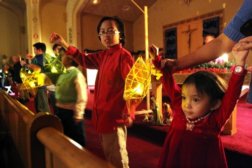 Rick Egan   |  The Salt Lake Tribune
From left, Eman Mendoza (green sweater), 8, Sam Mendoza, 11, and 3-year-old Nicole Mendoza, hold handmade lanterns during Mass at Our lady of Lourdes on Wednesday.