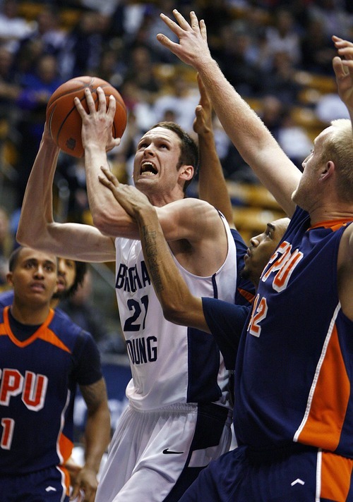 Djamila Grossman  |  The Salt Lake Tribune

Brigham Young University's Stephen Rogers, 21, pushes past Fresno Pacific University's Deshaun Legree, 15, and Tyler Goslinga, 42, during the second half of a game in Provo, Saturday, Jan. 1, 2011. BYU won the game.