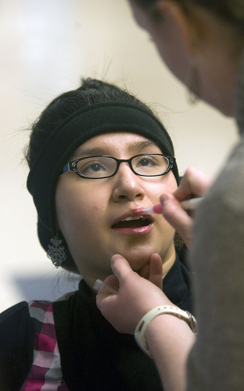 Al Hartmann  |  The Salt Lake Tribune 
Lina Nguyen was paralyzed in a car accident shortly before her junior year of high school. After a year and a half, she's returning to Granger High School to finish her senior year and graduate with her class.
Her aide Jennie Figueroa applies some lip gloss between classes.