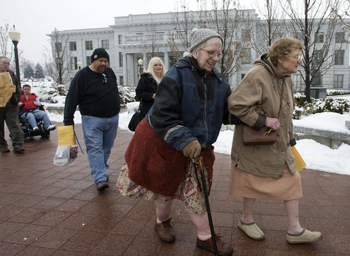 Al Hartmann  |  The Salt Lake Tribune 
Patricia VanVleet, center, and Nancy Falke, right, friends who share a house in Woods Cross and members of the Disability Action Committee,  walk together to the Governor's Office on Tuesday.