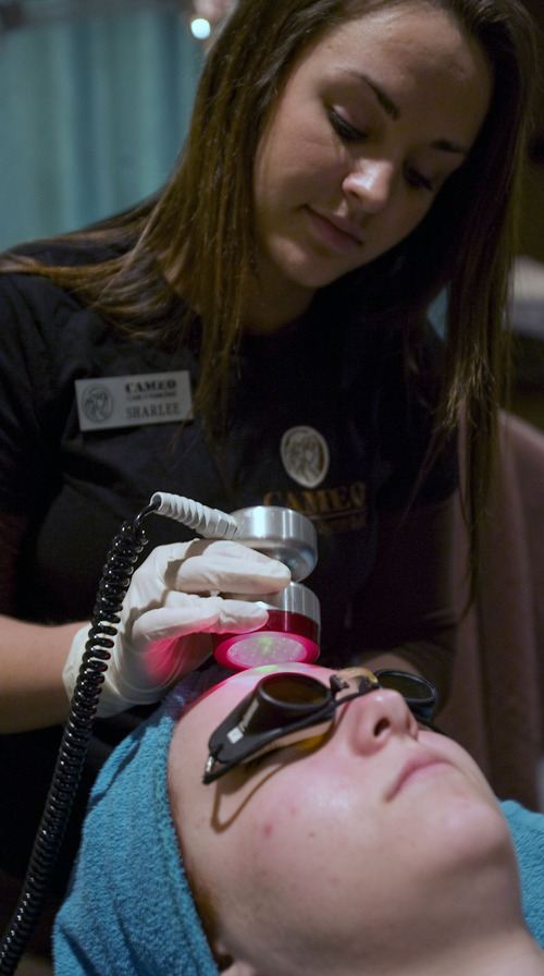 Al Hartmann   |  The Salt Lake Tribune 
Aesthetician student Sharlee Latta, top, gives an LED light therapy treatment to student Stephanie Acasay at the Cameo School of Essential Beauty in Muray. A Utah lawmaker is pushing a bill to require aestheticians to be supervised by a licensed physician.