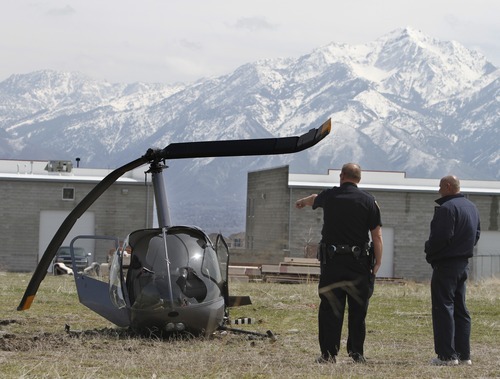Rick Egan   |  The Salt Lake Tribune
Officer checks out helicopter that made a hard landing in a field near South Valley Regional Airport Wednesday. The instructor and his student were on a training flight when the copter's engine failed They were treated at the scene and released.