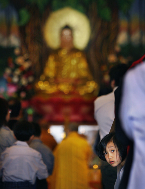 Scott Sommerdorf  |  The Salt Lake Tribune
A young girl peeks back at the main doors of the newly opened Lien Hoa Buddhist Temple as a ceremony around a the image of Buddha is underway. The Lien Hoa Buddhist Temple opened Sunday after a decade of planning. in West Valley CIty Sunday, April 17, 2011.