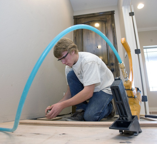 Al Hartmann   |  The Salt Lake Tribune
Ben Miles, a junior at Riverton High School, lays a hardwood floor piece in an entryway. He is among a team of students at Canyons Technical Education Center building a house as part of class at 569 E. Rose Bowl Court in Sandy. They will sell the house to fund the construction-education program. Last year's house garnered $361,000.