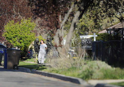 Sarah A. Miller  |  The Salt Lake Tribune

SWAT team members walk with a woman who came outside from the home on Westwood Ave. where Arturo M. Chvez was staying Thursday morning April 28, 2011 in Salt Lake City. Police, SWAT and JCAT had been on the scene since midnight waiting for Chavez  who had a warrant out for his arrest on the third degree felony drug charge. Chavez was arrested Thursday morning. The woman and Chavez had been subjected to tear gas.