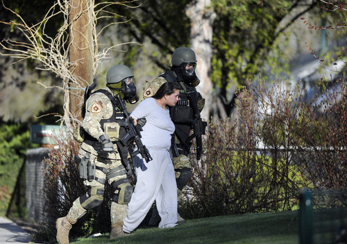Sarah A. Miller  |  The Salt Lake Tribune

SWAT team members walk with a woman who came outside from the home on Westwood Ave. where Arturo M. Chavez was staying Thursday morning April 28, 2011, in Salt Lake City. Police, SWAT and JCAT had been on the scene since midnight waiting for Chavez  who had a warrant out for his arrest on the third degree felony drug charge. Chavez was arrested Thursday morning. The woman and Chavez had been subjected to tear gas.