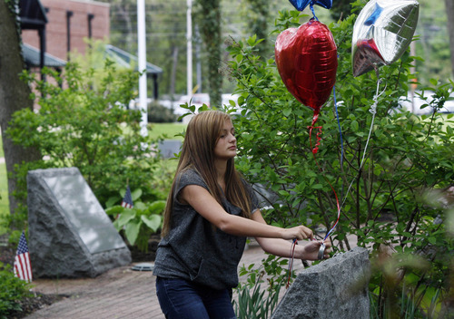 Fourteen-year-old Kristen Grazioso places balloons on a carved stone Monday, May 2, 2011, in Middletown, N.J., that  honors her father, who was killed in the attacks on the World Trade Center on Sept. 11, 2001. There are 37 stones in the garden representing those from Middletown who died in the attack. Word came late Sunday, May 1, 2011 the Osama Bin Laden has been killed. (AP Photo/Mel Evans)