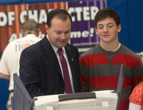 Al Hartmann  |  The Salt Lake Tribune
Mike Lee votes at Alpine Elementary School. His son James, alongside the voting booth, watches.