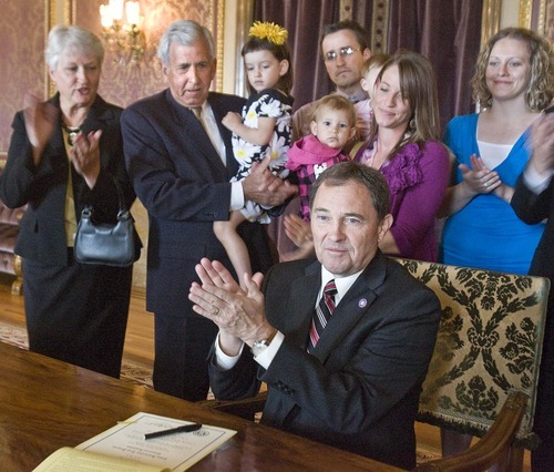 Paul Fraughton  |  The Salt Lake Tribune
Gov. Gary Herbert, with the family of the late Brian Cardall standing behind him, applauds Wednesday after signing a resolution encouraging police departments to participate in crisis intervention training. From left, Margaret Cardall and Duane Cardall, holding  Brian's daughter Ava (4), Brian's wife, Anna Cardall, holding daughter Bella (18 months), Brian's brother Craig, holding his son Cadence and his wife, Heather.