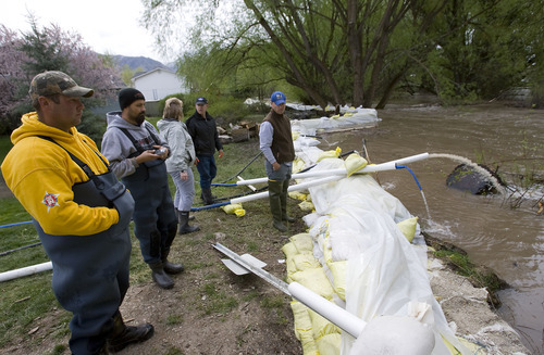 Al Hartmann  |  The Salt Lake Tribune
Homeowners of Country Manor Estates continued to watch the rising Blacksmith Fork River level Monday morning along the wall of sandbags protecting their homes.