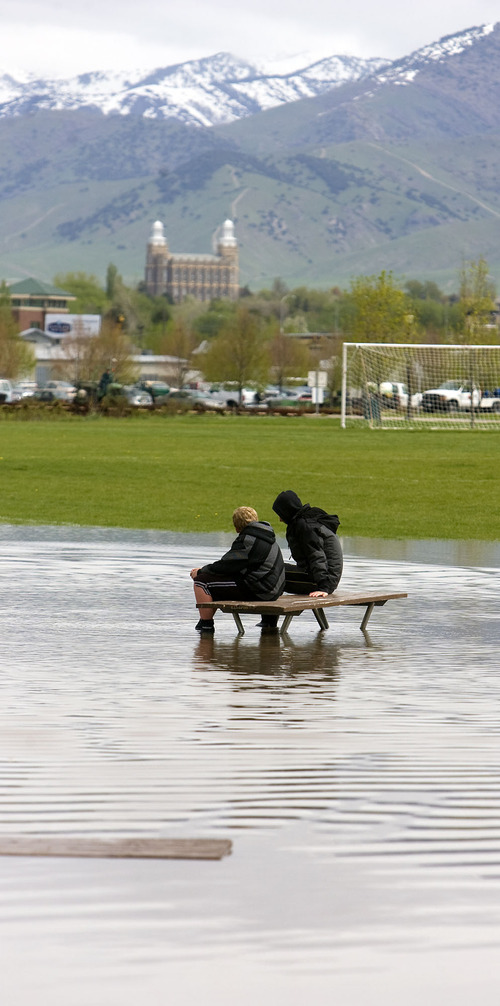 Al Hartmann  |  The Salt Lake Tribune
Landen Andersen, 12, left, and friend Jaden Cooley, 15, take a break Monday from protecting the Country Manor Estate from flooding, sitting on a partially submerged picnic table in a new lake formed in the soccer park next to the subdivision along the Blacksmith Fork River. They had been up most of the night with their parents watching the Blacksmith Fork River continue to creep up its banks.