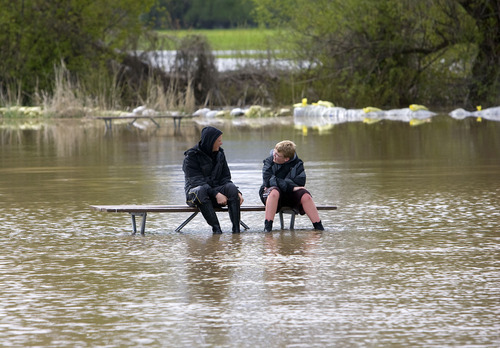 Al Hartmann  |  The Salt Lake Tribune
Jaden Cooley, 15, and friend Landen Andersen, 12, take a break from the flooding of Country Manor Estate, sitting on a partially submerged picnic table Monday in a new lake formed in the soccer park next to the subdivision along the Blacksmith Fork River. They had been up most of the night with their parents watching the Blacksmith Fork River continue to creep up its banks.