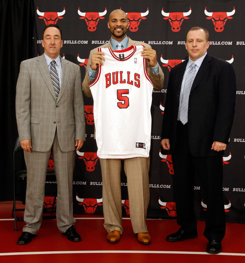 Kamil Krzaczynski  |  For The Salt Lake Tribune 
Carlos Boozer holds his new Chicago Bulls jersey during the press conference with Chicago Bulls General Manager Gar Forman, left, and Chicago Bulls head coach Tim Thibodeau on July 9, 2010.