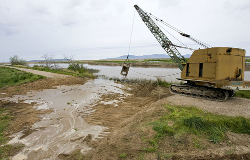 Al Hartmann  |  The Salt Lake Tribune
A drag line is used to open a breach in a dike road at the Ogden Bay Wildlife Management Area west of Hooper to help alleviate the swollen Weber River on Thursday. Two breached dikes in the area may not be enough to stop flooding.