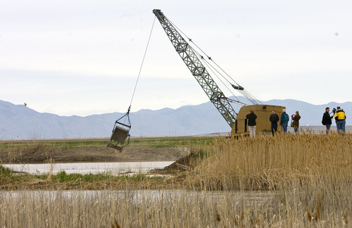 Al Hartmann  |  The Salt Lake Tribune
A drag line is used to open a breach in a dike road at the Ogden Bay Wildlife Management Area west of Hooper to help alleviate the swollen Weber River on Thursday. Two breached dikes in the area may not be enough to stop flooding.