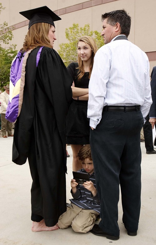 Trent Nelson  |  The Salt Lake Tribune
Jett Gale plays a videogame after his mother, Jaymi Gale, left, received her MBA at Westminster College's Commencement Exercises at the Maverik Center in West Valley City, Utah, on Saturday. At center is Maddie Gale and right is Tim Gale.