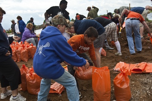 Photo by Chris Detrick | The Salt Lake Tribune 
Isaac Dixon, 11, in blue, and Bridger Jensen, 9, help to fill up sand bags as water from the Weber River floods near homes in West Warren Thursday June 9, 2011.  Around 7:30 a.m., Weber County officials were gasing up diesel pumps used to divert the waters when they saw the levee break. Three of the pumps are now submerged and by noon, floodwaters near the levee were a foot above flood stage and climbing.