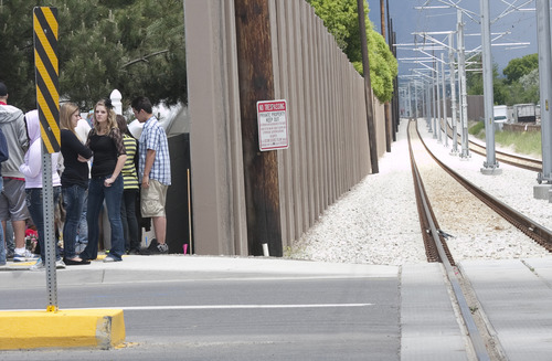 File photo  |  The Salt Lake Tribune
Utah Transit Authority has decided to remove sections of sound wall that are obstructing pedestrian visibility at TRAX intersections on the the new Mid-Jordan line. This photo from last Thursday shows a group of friends gathered near a memorial placed at the site where Shariah Casper, 15, was struck and killed by a train the previous day.