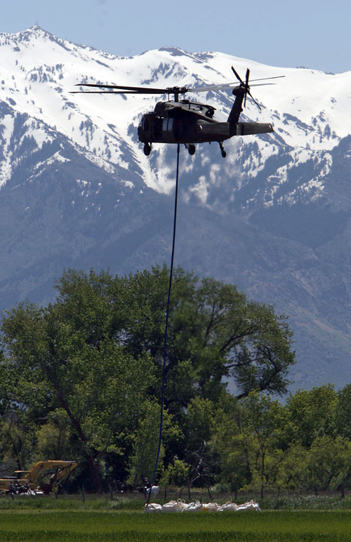 Francisco Kjolseth  |  The Salt Lake Tribune
With much snow still in the mountains, large sandbags are moved by Black Hawk helicopters in an effort to shore up a broken levee. Weber County's Incident command manages the repairs along the Weber River in West Warren on Friday, June 10, 2011, with help from the Utah National Guard and contractor Randy Marriott Construction. Two black hawk helicopters were brought in to move large sand bags into the area while ground crews try to shore up the area that breached to hold the bags in place.