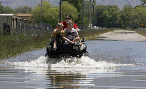 Francisco Kjolseth  |  The Salt Lake Tribune
Mindy Lambert drives through high water with her two children Brody, 5, left, and Aubree, 8, after looking at a breach in the Weber River in West Warren where the three went to have a look. Weber County's Incident command manages repairs to a broken levee along the Weber River in West Warren on Friday, June 10, 2011, with help from the Utah National Guard and contractor Randy Marriott Construction. Two black hawk helicopters were brought in to move large sand bags into the area while ground crews try to shore up the area that breached to hold the bags in place.