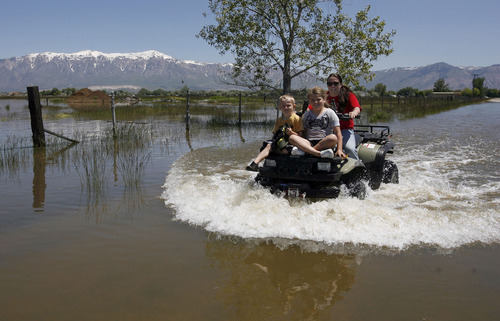 Francisco Kjolseth  |  The Salt Lake Tribune
Mindy Lambert drives through high water with her two children Brody, 5, left, and Aubree, 8, after looking at a breach in the Weber River in West Warren where the three went to have a look. Weber County's Incident command manages repairs to a broken levee along the Weber River in West Warren on Friday, with help from the Utah National Guard and contractor Randy Marriott Construction. Two black hawk helicopters were brought in to move large sand bags into the area while ground crews try to shore up the area that breached to hold the bags in place.