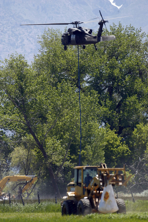 Francisco Kjolseth  |  The Salt Lake Tribune
Ground crews maneuver large sandbags for Black Hawk helicopters to pick up in an effort to shore up a broken levee. Weber County's Incident command manages the repairs along the Weber River in West Warren on Friday, with help from the Utah National Guard and contractor Randy Marriott Construction. Two black hawk helicopters were brought in to move large sand bags into the area while ground crews try to shore up the area that breached to hold the bags in place.