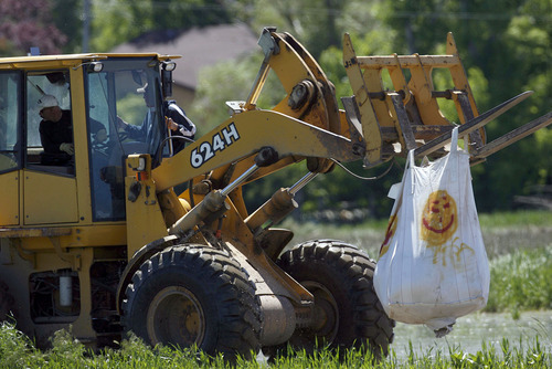 Francisco Kjolseth  |  The Salt Lake Tribune
Ground crews maneuver large sandbags for Black Hawk helicopters to pick up in an effort to shore up a broken levee. Weber County's Incident command manages the repairs along the Weber River in West Warren on Friday, with help from the Utah National Guard and contractor Randy Marriott Construction. Two black hawk helicopters were brought in to move large sand bags into the area while ground crews try to shore up the area that breached to hold the bags in place.