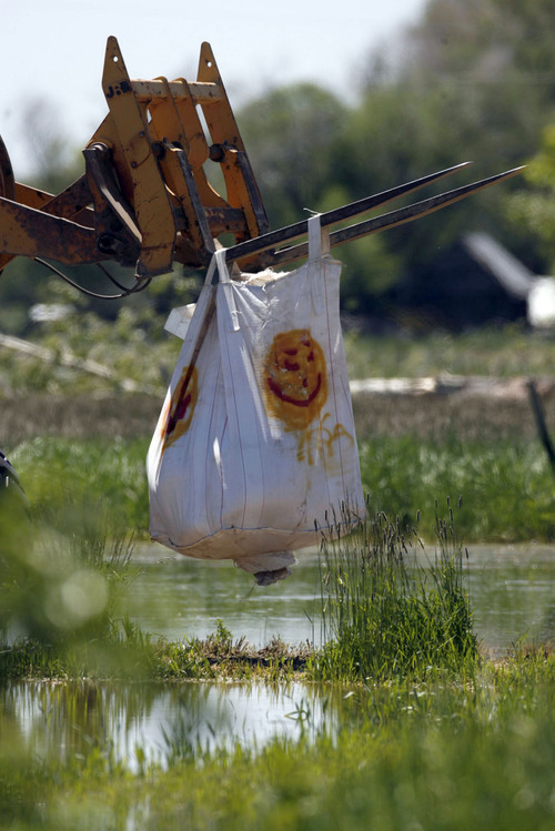 Francisco Kjolseth  |  The Salt Lake Tribune
Ground crews maneuver large sandbags for Black Hawk helicopters to pick up in an effort to shore up a broken levee. Weber County's Incident command manages the repairs along the Weber River in West Warren on Friday, June 10, 2011, with help from the Utah National Guard and contractor Randy Marriott Construction. Two black hawk helicopters were brought in to move large sand bags into the area while ground crews try to shore up the area that breached to hold the bags in place.